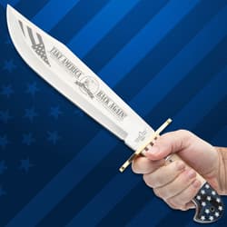 Knife held in hand, showing engraved blade and handle