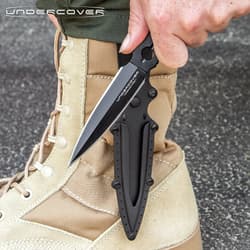 Person drawing black dagger from boot sheath