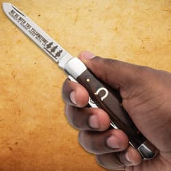 Hand holding a pocket knife with engraved blade