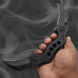 Hand holding a black folding knife with dual blades