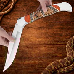 Hands holding open folding knife on wooden background