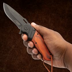 Hand holding Timber Wolf pocket knife with wood handle