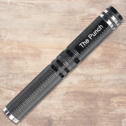 Closed metal punch tool with textured grip on wooden surface