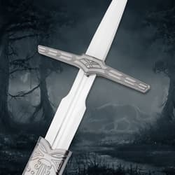 Close-up of sword hilt with engraved design, wolf in misty forest