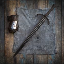 Black sword on chainmail and armor piece on wooden surface