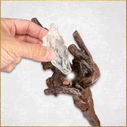 Hand placing crystal on wooden staff with light effect