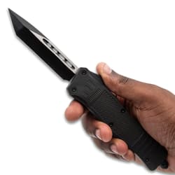 Hand holding a black tactical knife