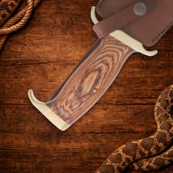 Close-up of Bowie knife handle and sheath on wood
