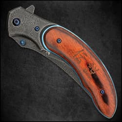 Open shinwa shinigami bloodwood pocket knife with raindrop pattern blade, metallic blue accents, and engraved bloodwood handle scales.