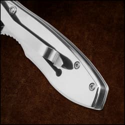 Close-up of a metallic folding knife handle on a brown background