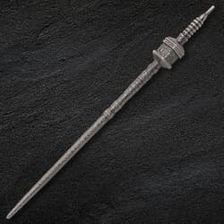 Intricately designed metal needle on a dark textured surface