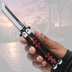 Hand holding butterfly knife with black handle and red accents, cherry blossom background