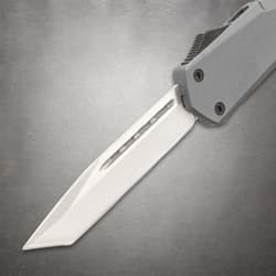 Sharp blade of a tactical knife against a gray background