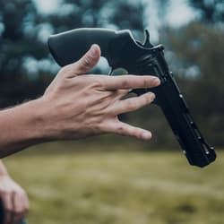 Person holding black air pistol outdoors