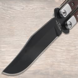 Close-up of butterfly knife's black blade on wood background