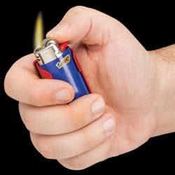 Hand holding black pocket knife lighter caddy containing blue "BIC" lighter that has been lit by the hand's thumb.