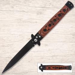Black stiletto knife with wooden handle on wood background