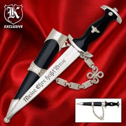 Decorative dagger with black handle and silver accents on red fabric