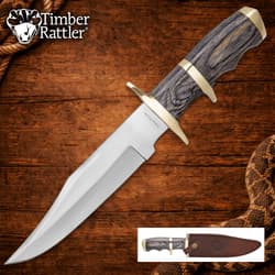 Knife with wooden handle and brass guard on wooden background