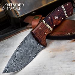 Damascus steel knife with wooden handle on leather sheath