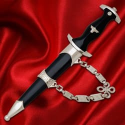 Black-handled dagger with silver details and chain on red fabric