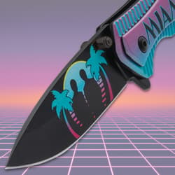 Close-up of knife blade with palm trees and silhouettes