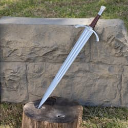 Sword with brown handle leaning against stone and wood outdoors