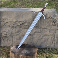 Knight sword embedded in a tree stump against a stone wall