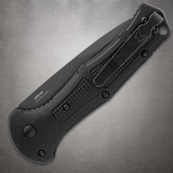 Closed black knife with pocket clip on gray background