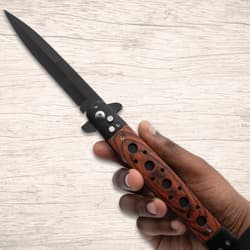 Hand holding a stiletto knife with wooden handle