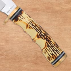 Close-up of burnt jigged bone handle on wood