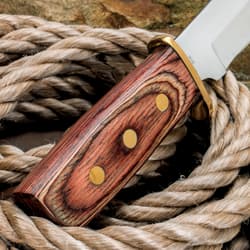 Close-up of knife handle with brass rivets on rope