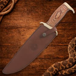 Bowie knife in leather sheath on wooden background