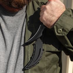 Person holding black knife in sheath on jacket