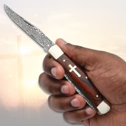 Hand holding a pocket knife with cross inlay