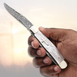 Hand holding a pocket knife with cross inlay