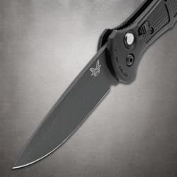 Close-up of black knife blade with logo on gray surface