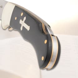 Close-up of knife handle with cross inlay on open book