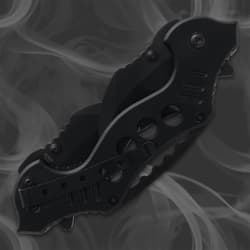 Closed black folding knife with pocket clip on smoky background
