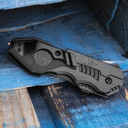 Closed tactical knife with clip on blue wooden surface