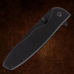 Closed black folding knife on brown background
