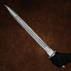 Damascus sword held in a gloved hand on brown background
