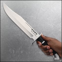 Hand holding a large knife with a black handle
