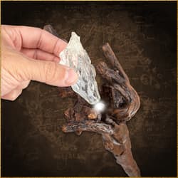 Hand placing crystal into Gandalf's staff, illuminating it