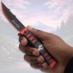 Hand holding a black and red knife with anime design
