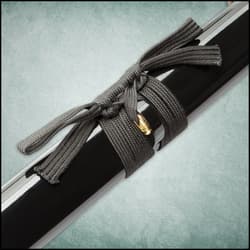 The black braided cord of the scabbard surrounds a gold detail.