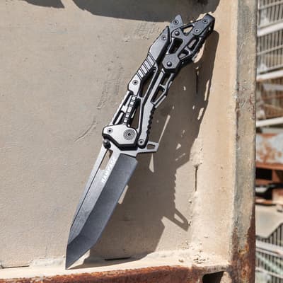 Knife with black blade resting on a concrete surface