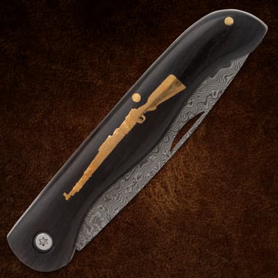Closed folding knife with rifle inlay on dark handle