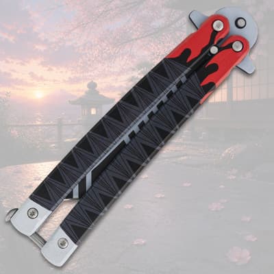 Closed butterfly knife with flame design on a scenic background
