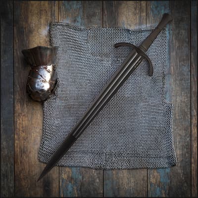 Black sword on chainmail and armor piece on wooden floor